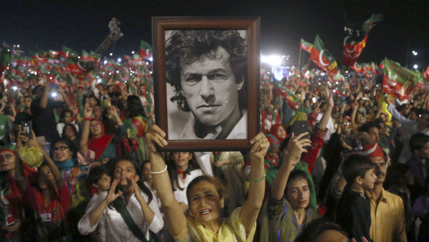 A woman supporter of Tehreek-e-Insaf party raises a picture of her party's leader Imran Khan during an election campaign rally in Karachi.