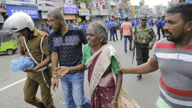 Sri Lankan elderly woman is helped near St Anthony's Shrine after a blast in Colombo, Sri Lanka.
