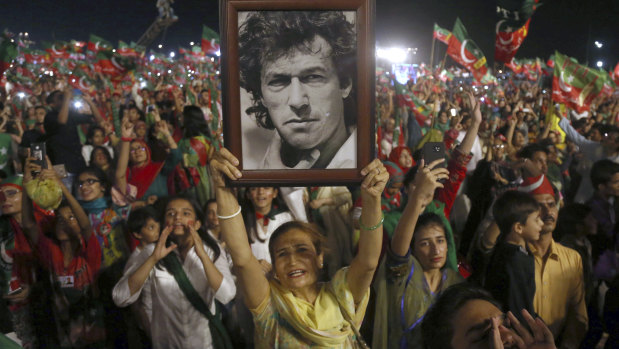 A woman supporter of Tehreek-e-Insaf party raises a picture of her party's leader former cricketer Imran Khan during a rally in Karachi on Sunday.