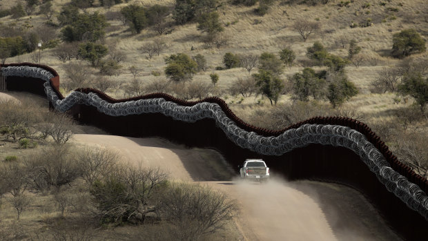 A Customs and Border Control agent patrols on the US side of a razor-wire-covered border wall along the Mexico east of Nogales, Arizona.