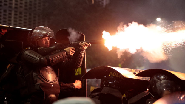 A riot police officer fires his tear gas launcher at supporters of Indonesian presidential candidate Prabowo Subianto during a clash in Jakarta, Indonesia.