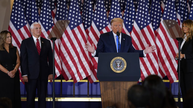 President Donald Trump speaks in the East Room of the White House, early on Wednesday in Washington, as Vice President Mike Pence and Karen Pence and first lady Melania Trump listen. 