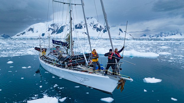 Bertie Gregory, Ralph Bower and Spencer Millsap posing for a photo while pushing icebergs out of the way of the boat with metal poles.  