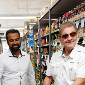 Altona IGA owner Hitesh Palta, left, with a customer. His supermarket was the first to introduce an elderly-only shopping hour.