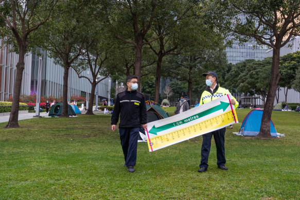 Security guards patrol with a social distancing sign at Tamar Park in Hong Kong, on Sunday, February 13.