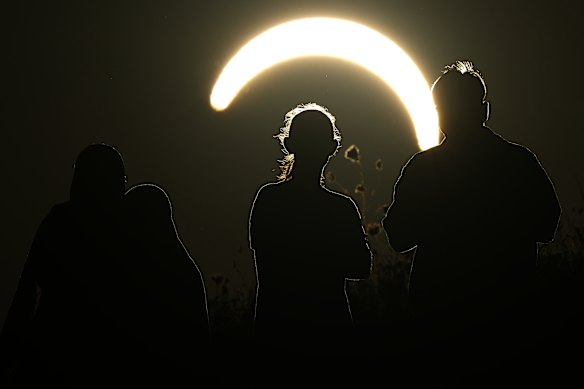 People observing a partial eclipse at Northala Fields in London.