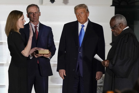 President Donald Trump watches as Supreme Court Justice Clarence Thomas administers the Constitutional Oath to Amy Coney Barrett at the White House in Washington, on Monday night (Tuesday AEDT).