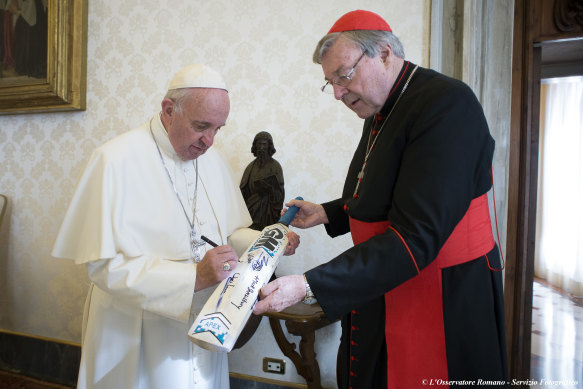 Pope Francis signs a cricket bat he received from Cardinal George Pell in 2015.
