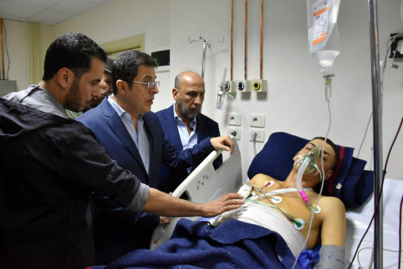 Syrian Health Minister Hassan al-Ghabash, centre, checking a man injured in the drone attack.