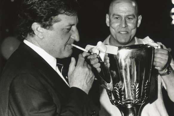 John Elliott lights up as ex-Carlton player Des English holds the premiership cup.