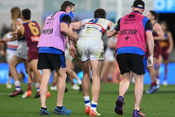 Marcus Bontempelli is helped off the Gabba on Saturday night.