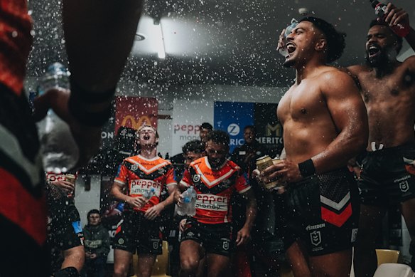Lachlan Galvin (left) celebrates with Tigers teammates Api Koroisau, Fonua Pole and Sunia Turuva in the Leichhardt Oval sheds.