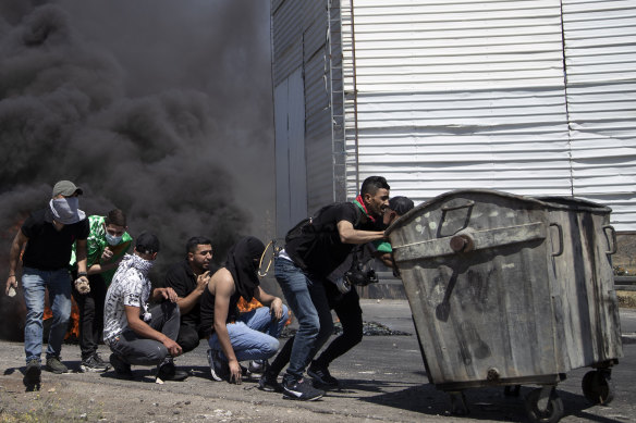 Palestinian demonstrators take cover during clashes with Israeli forces at the Hawara checkpoint, south of the West Bank city of Nablus, on Friday.