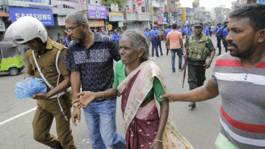 Sri Lankan elderly woman is helped near St. Anthony's Shrine after a blast in Colombo, Sri Lanka.
