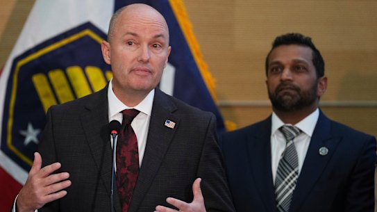 Utah Governor Spencer Cox speaking at a news conference, as FBI Director Kash Patel looks on.