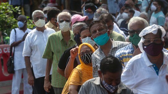 People queue in Mumbai, India, on Monday to receive their COVID-19 vaccine.