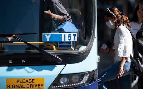 A woman wearing a protective face mask boards a bus in Sydney.