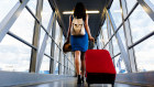 Young girl traveler walking with carrying hold suitcase in the airport. Tourist Concept. Photo: iStock
