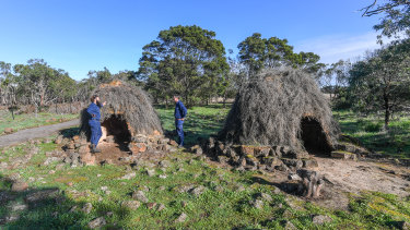 Budj Bim rangers Aaron Morgan and Leigh Boyer stand by replica stone houses. 