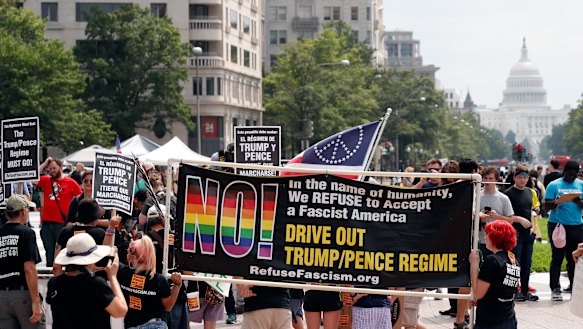 Groups protest in Freedom Plaza, Washington, with the US Capitol in the background.