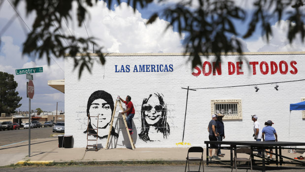 Manuel Oliver works on a mural in El Paso, Texas. It reads: "The Americas belong to everyone". The shooting that killed more than 20 people on Saturday is being handled as a domestic terrorism case.