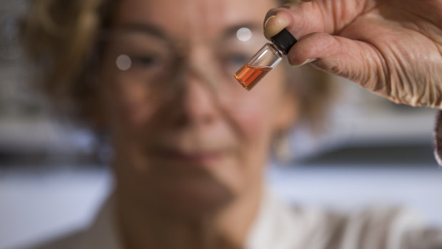 Australian National University biogeochemistry lab manager Janet Hope holds a vial of pink coloured porphyrins representing the oldest intact pigments in the world.
