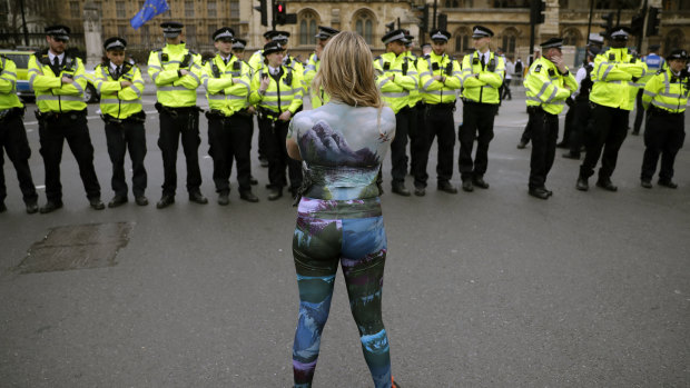 A protester, with half of her body covered in body paint, faces police during a protest in Parliament Square on Tuesday by the group Extinction Rebellion.