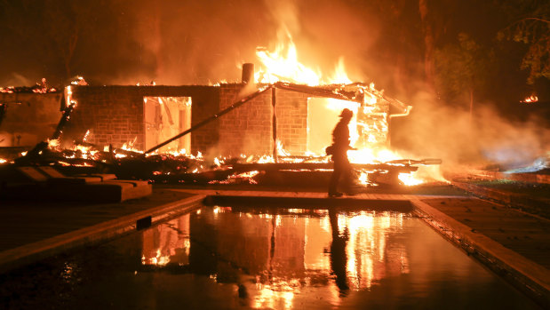 A firefighter walks by a burning home in Malibu, California.