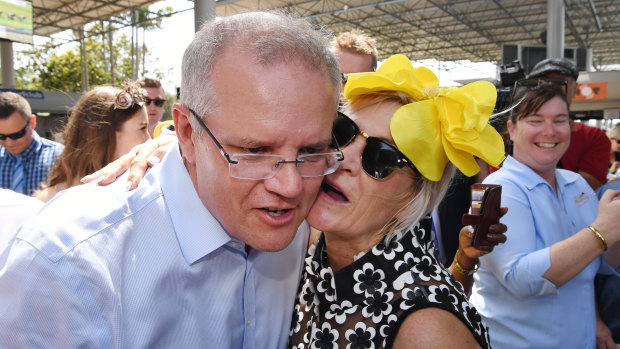 The Prime Minister is kissed by a racegoer on Melbourne Cup Day at the Corbould Park Racecourse at the Sunshine Coast.
