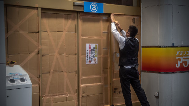 A man covers over a doorway ahead of the arrival of Typhoon Hagibis.