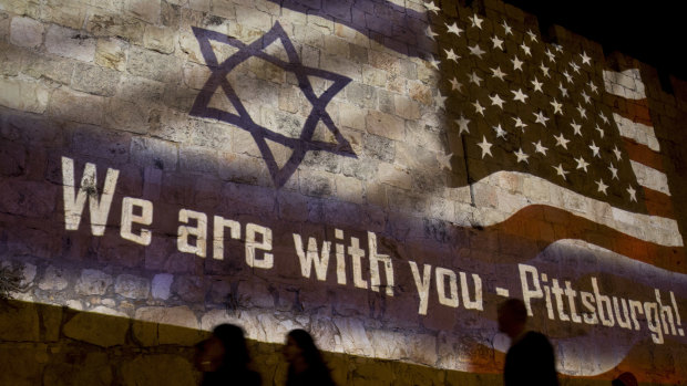 People walk past a projection on the Old City wall in Jerusalem on Sunday in a commemoration of the victims of a deadly shooting at a Pittsburgh synagogue.