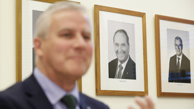 A portrait of former Nationals leader Barnaby Joyce hangs on the wall behind Deputy Prime Minister Michael McCormack. The new party leader has defended the Coalition's commitment to decentralisation. 