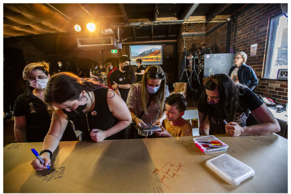 Mourners write on Steve Ellis’s coffin at the Tote Hotel.