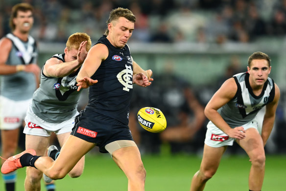 Patrick Cripps of the Blues kicks whilst being tackled by Willem Drew of the Power.