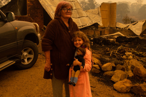 Barbara Rugendyke with one of her children, in front of their property which was devastated by bushfires.