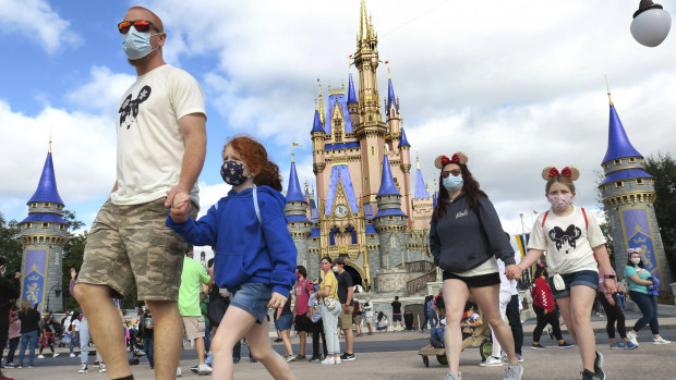 A masked family walk past Cinderella Castle at Walt Disney World in Lake Buena Vista, Florida. Wearing a mask is about safety for all.