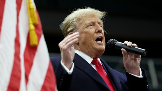 Former president Donald Trump speaks to voters during a visit to a caucus site in Clive, Iowa.
