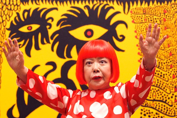  Japanese artist Yayoi Kusama poses for photographers in front of her painting “Love Arrives at the Earth Carrying with it a Tale of the Cosmos” at the Tate Modern in London, on Feb. 7, 2012.