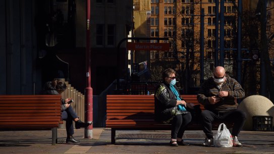 A couple wear face masks whilst sitting on a bench on Macquarie Street in Sydney, NSW. 18th August, 2020. Photo: Kate Geraghty Coronavirus