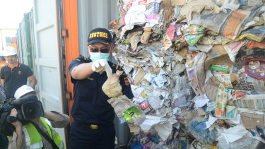 Indonesian Customs official Dhion Priharyanto holds up a used nappy, soft drink containers and a plastic of organic raspberries mixed in with paper that was supposed to be recycled. Instead, it will be sent back to Australia.