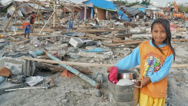 Ten-year-old Suci Rahmadi at Mamboro beach with pots and pans  she has collected from the debris. 