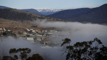 Fog lifting over Jindabyne in New South Wales with snow on the peaks surrounding it as the Snowy Mountains region prepares for the ski season to start