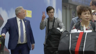 Australian student Alek Sigley arrives at the airport in Beijing with Swedish diplomat Kent Rolf Magnus Harstedt, left.