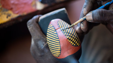 An artist painting a carving at Tiwi Design on Bathurst Island in the Northern Territory. 
