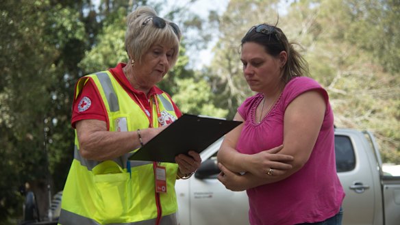 Courier driver Sophie Bryden (right), 38, speaks to Red Cross workers at Canungra Sports and Recreation Ground.