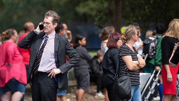 Parents and staff wait outside Epping Boys High School for a group of year nine boys to return from camp on Friday.