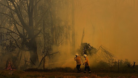 NSW RFS fire fighters surrounded by smoke as they work on battling a fire at Tahmoor, NSW. 