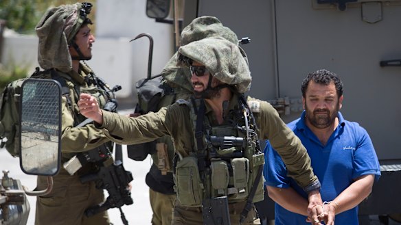 Israeli soldiers make one of several arrests of Palestinians last month after a soldier was killed by a rock thrown from a rooftop in the West Bank village of Yabad. 
