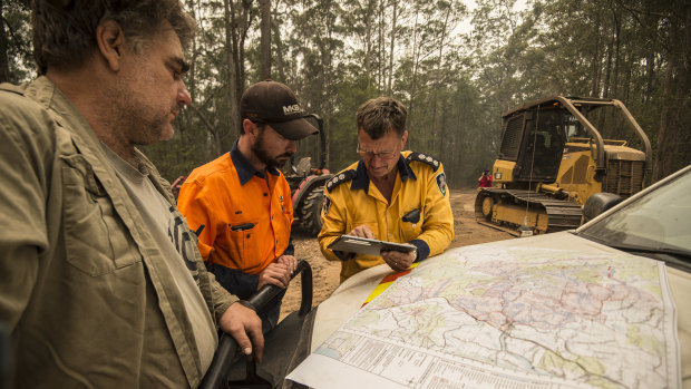 Property owners Brad Edge, Ben Donnelly and Anthony Roberts from the RFS discuss the fire map ahead of worsening weather conditions. 