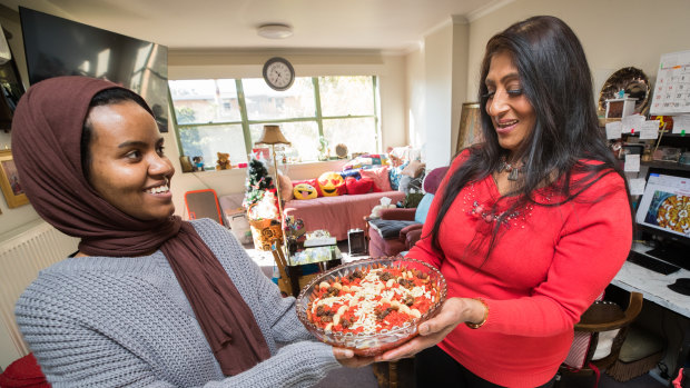 Deepa Gupta (in red) and
Furdus Suliman, one of the cookbook coordinators, share Gajar Hawa (Indian carrot pudding). 